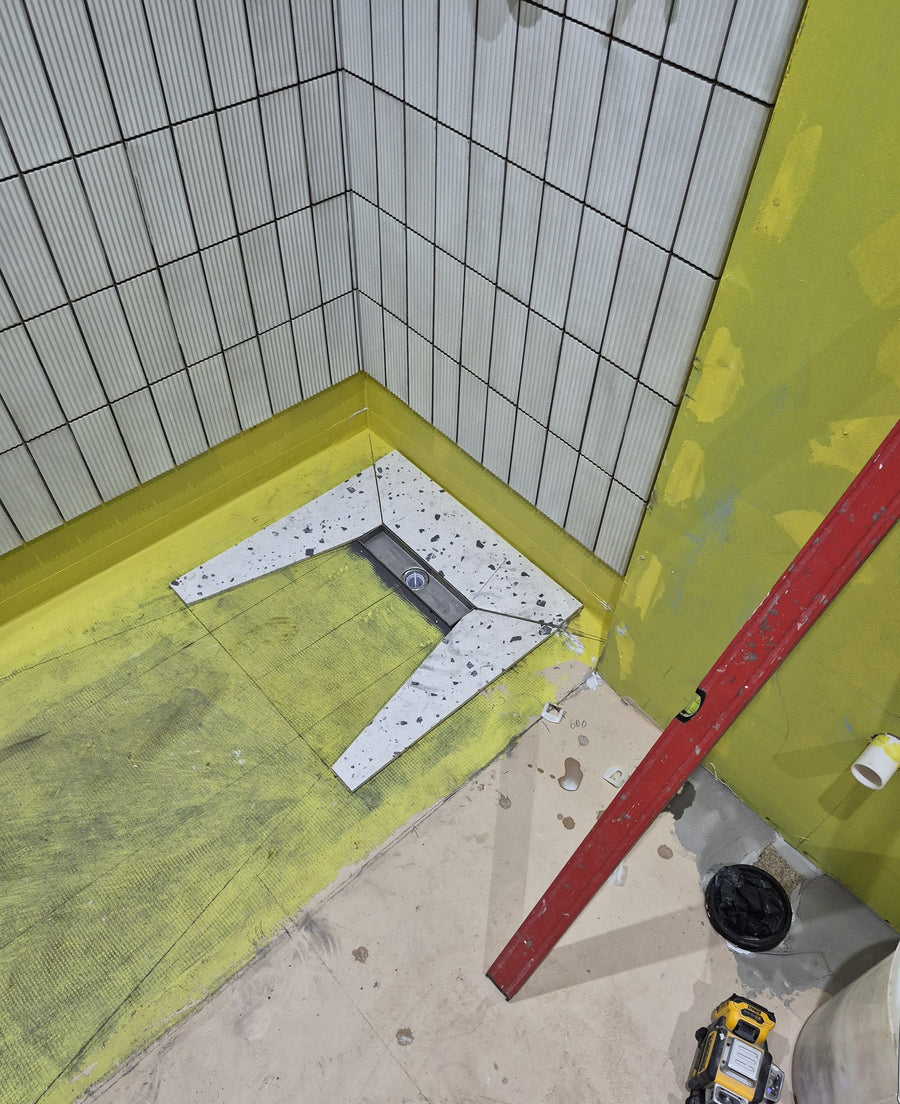 Terrazzo-effect floor tiles cut around the linear shower drain