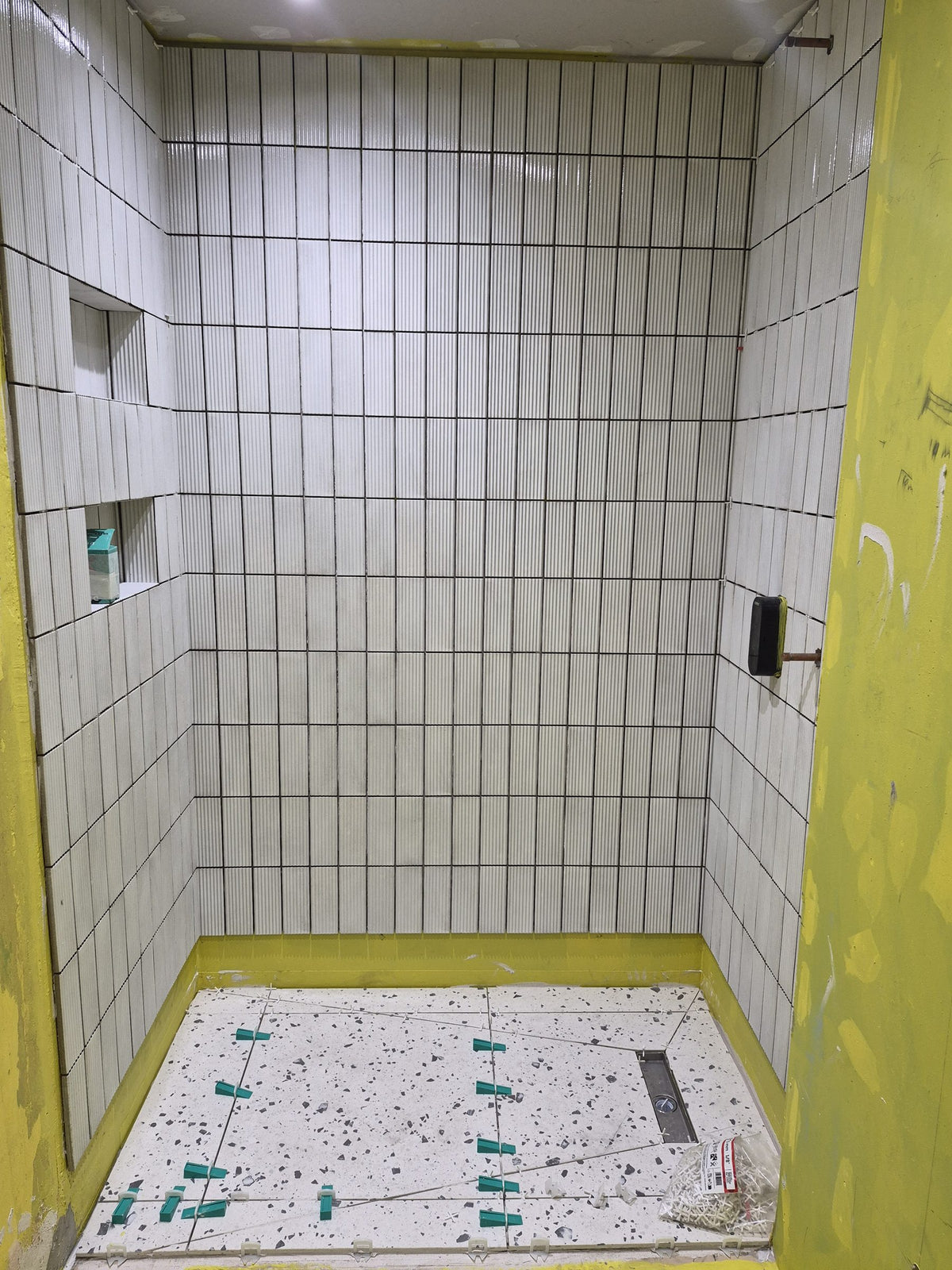Shower floor tiled using levelling clips, with the niches tiled