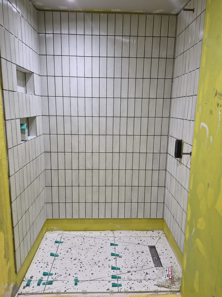 Shower floor tiled using levelling clips, with the niches tiled