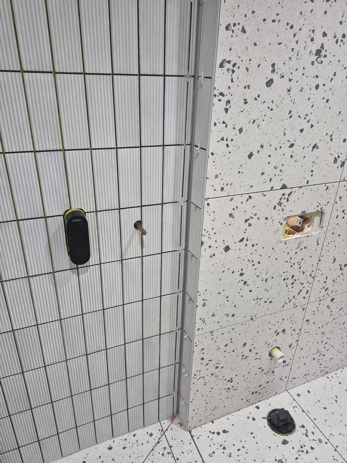 Metal trim finishing the corner where the fluted and terrazzo-effect tiles meet
