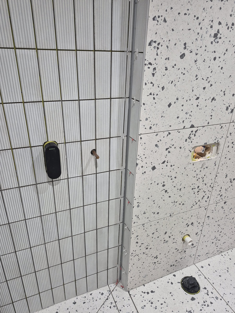 Metal trim finishing the corner where the fluted and terrazzo-effect tiles meet