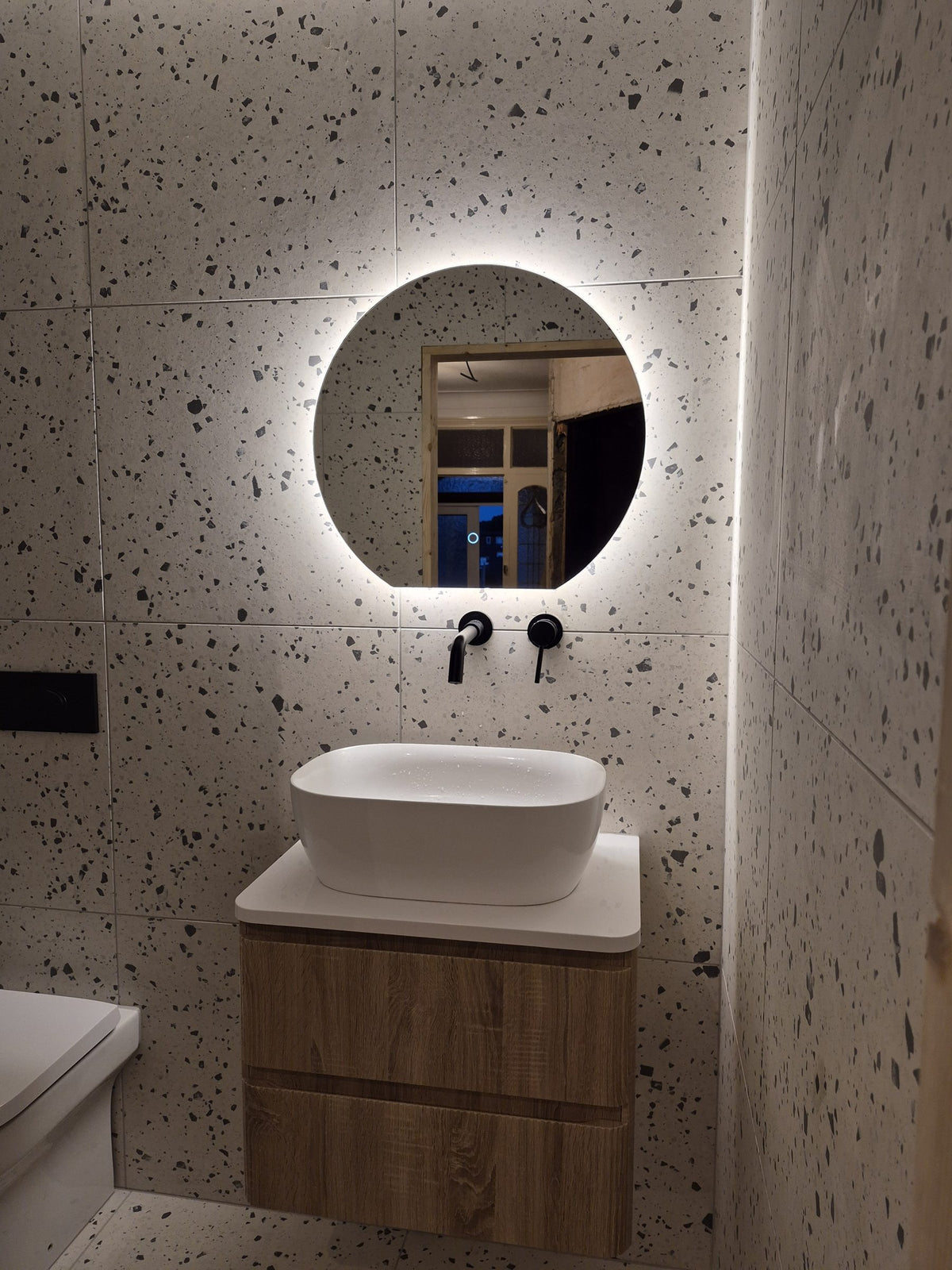 Wall-mounted matt black taps, backlit mirror and LED strip lighting