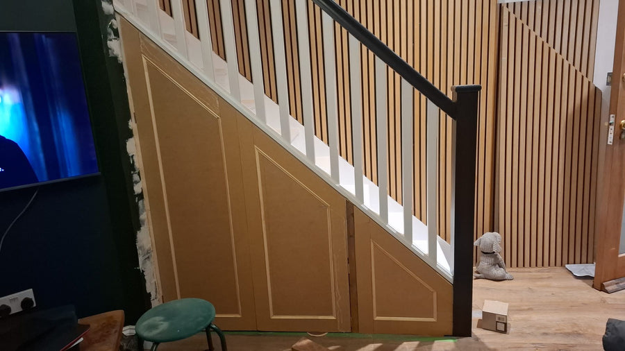 Staircase with vertical slatted panelling and a black handrail