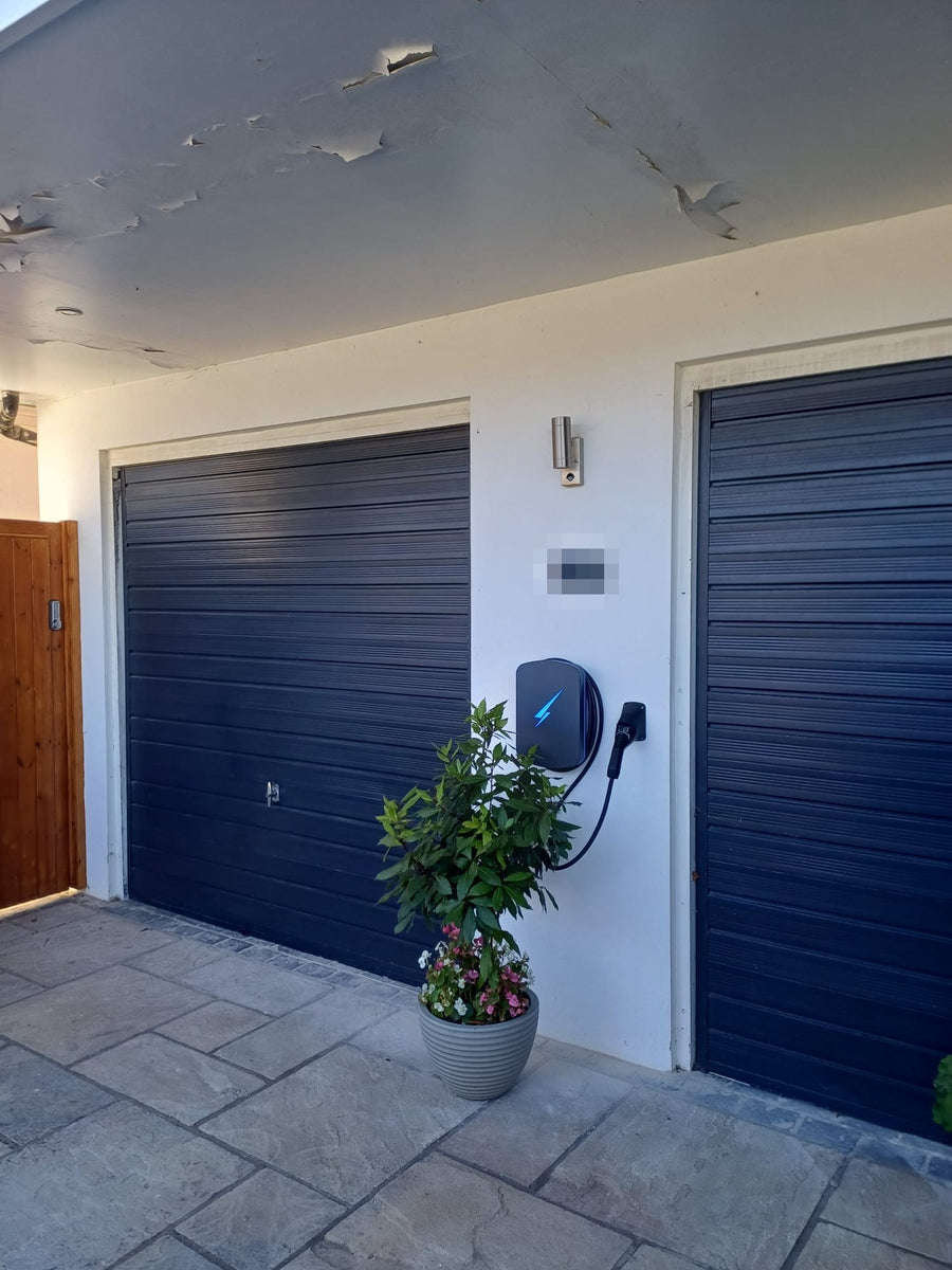 A home EV charger on the wall between two garage doors