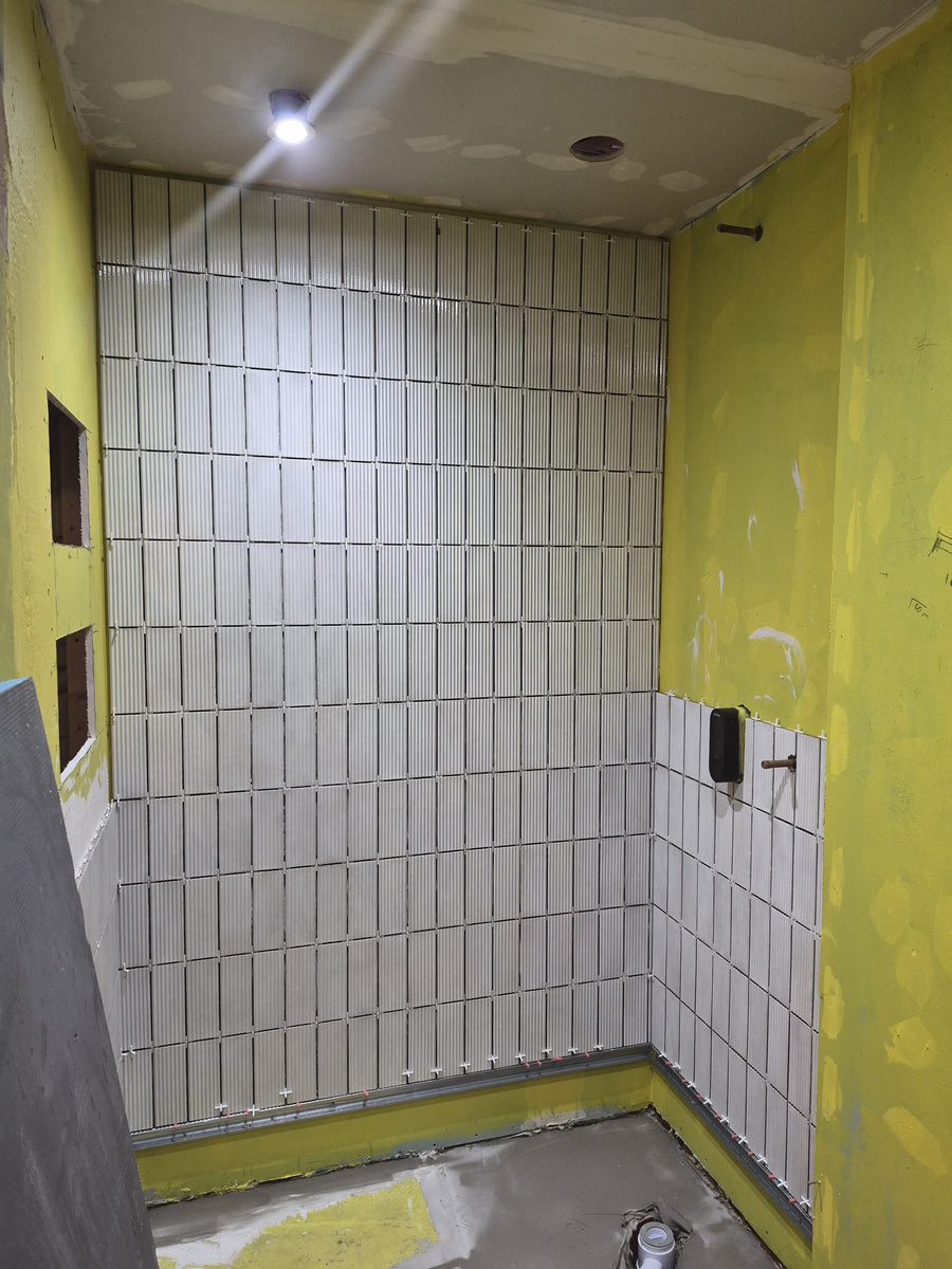 Shower walls waterproofed with tanking, and the first fluted tiles fitted